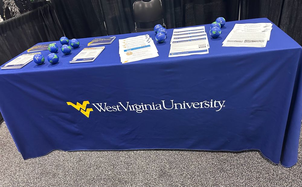Table covered with blue cloth and WVU logo with informational materials and little squishy globes