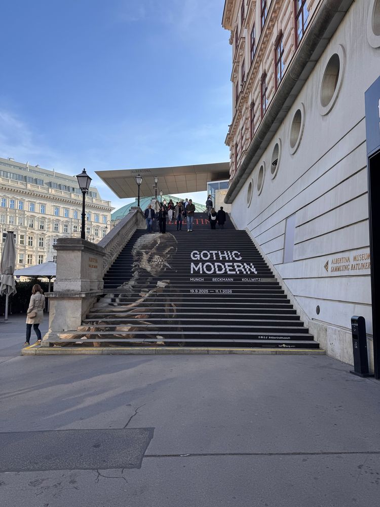 A staircase showing a painting and text on the vertical surfaces. It is a Van Gogh painting of a skeleton smoking. The text says “Gothic Modern”