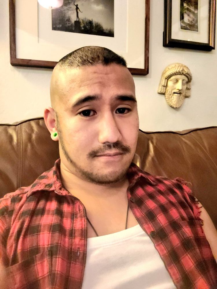 Relaxed face, white wifebeater, plaid shirt with sleeves ripped off