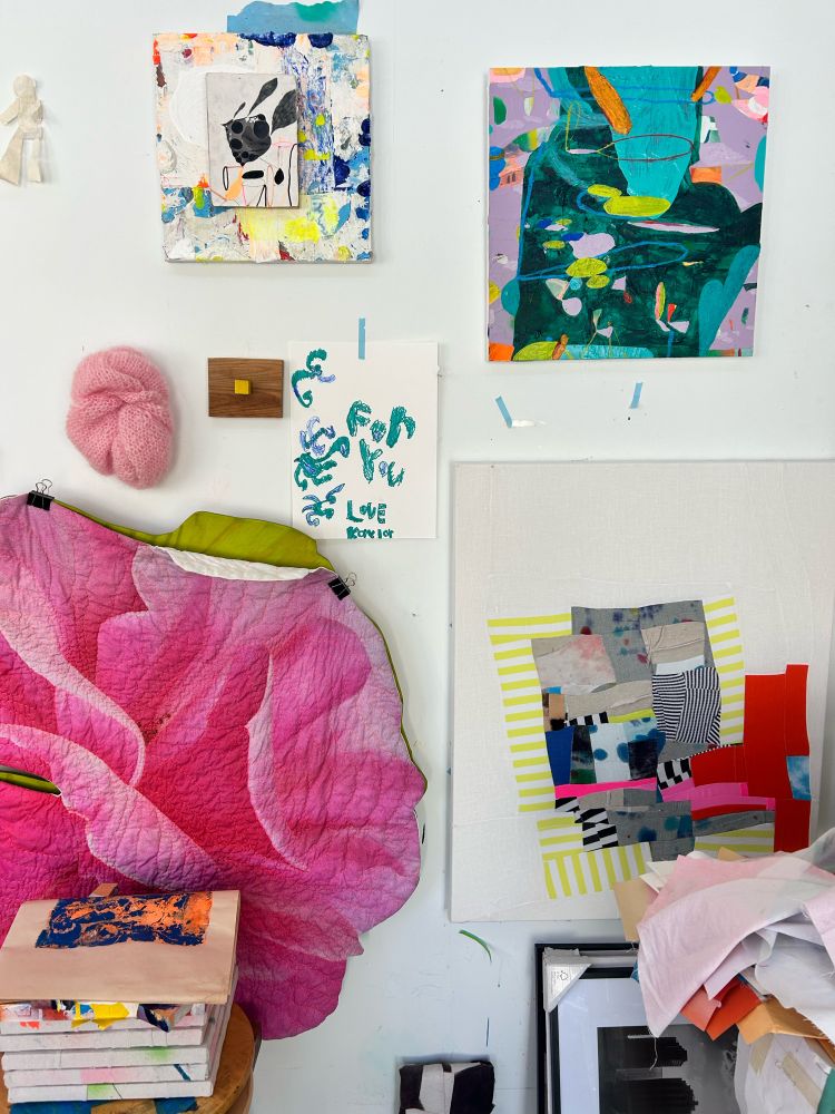 A white wall with abstract artwork, paintings, quilts, fabric collages, and constructions, around a drawing that says “for you, love Kaylor.”