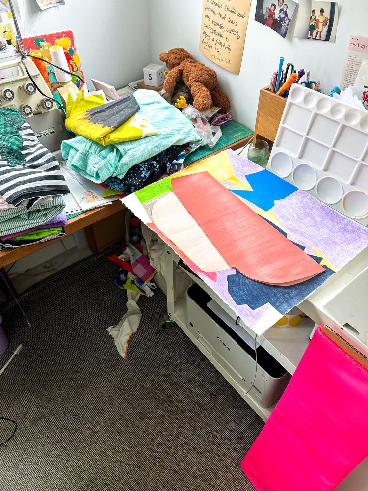 Studio corner with stacks of fabric and artwork. 