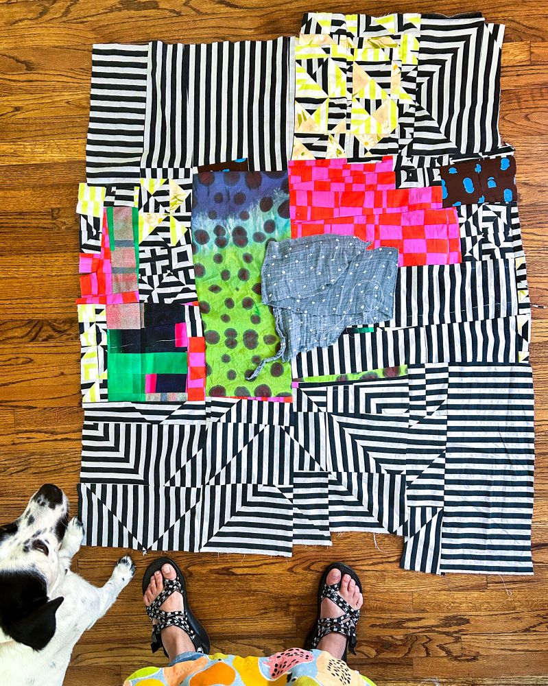 Maximalist quilt top in progress resting on a wood floor.  