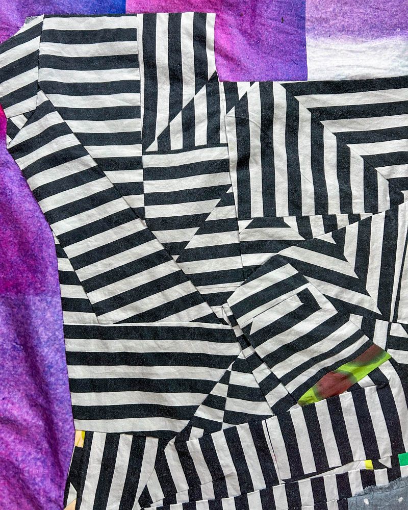 Detail of a quilt top with intersecting black and white lines. 