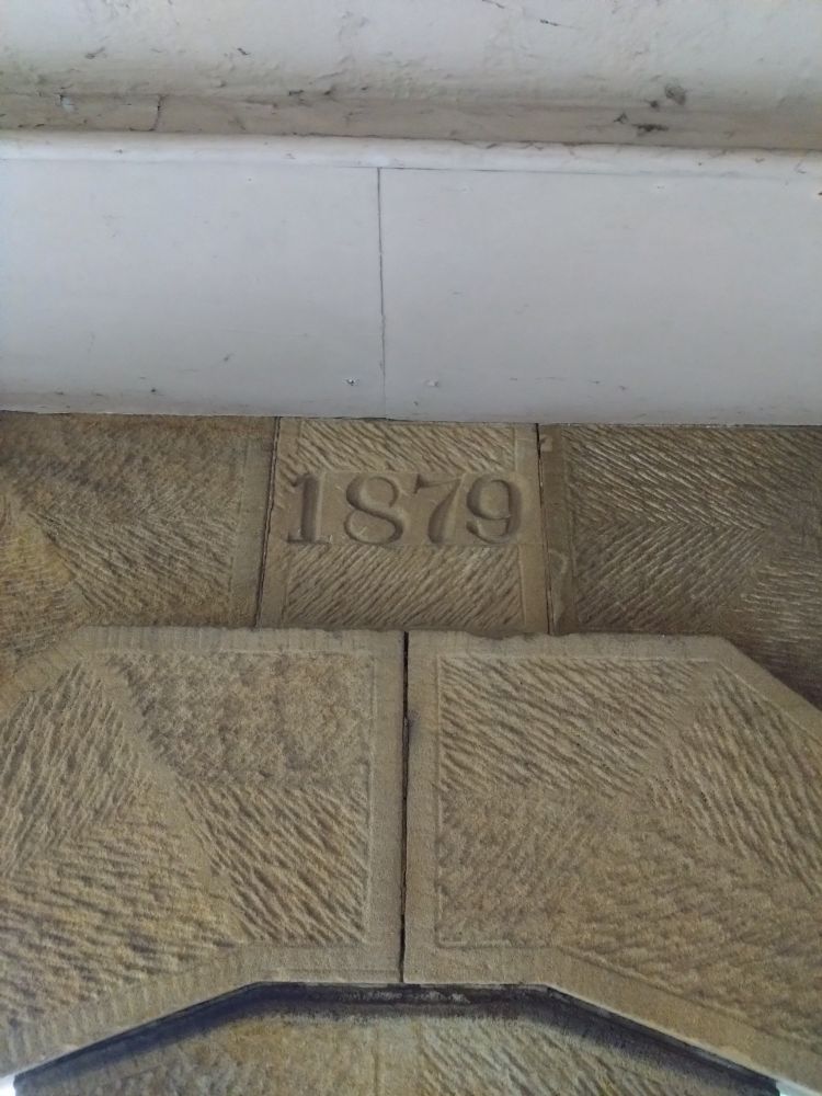 Sandstone wall. One brick has 1879 carved into it.