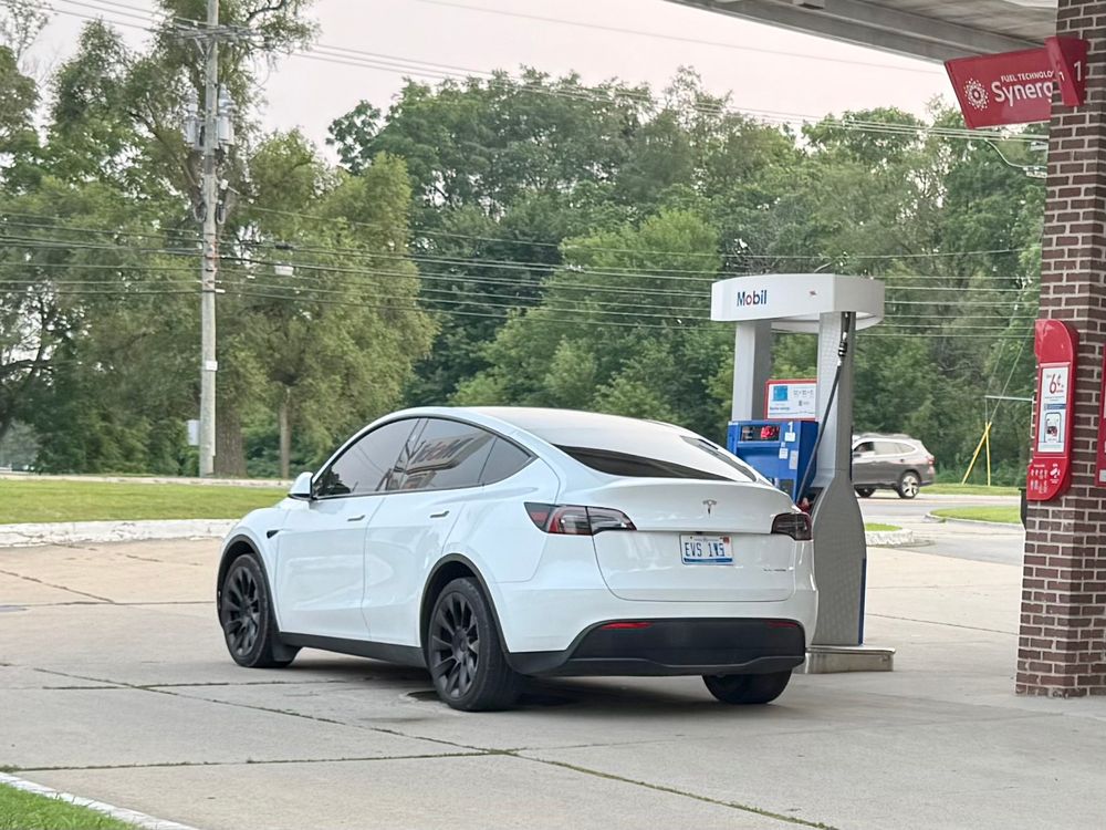 A white Tesla parked at a Mobile gas station fuel pump. 