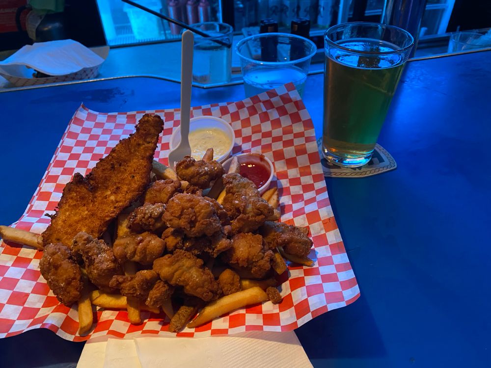 Big bowl of fried oysters and fried cod and fries with a beer