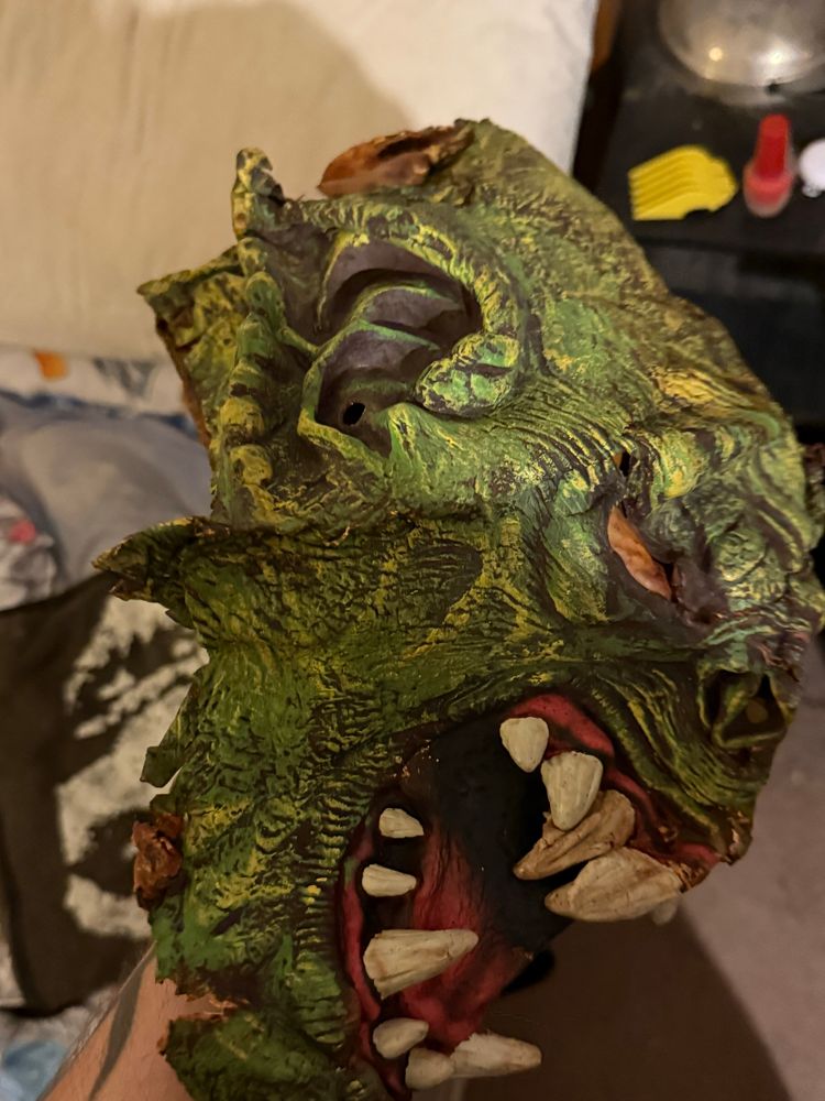 The right side of a green monster mask with pointed ears and big fangs