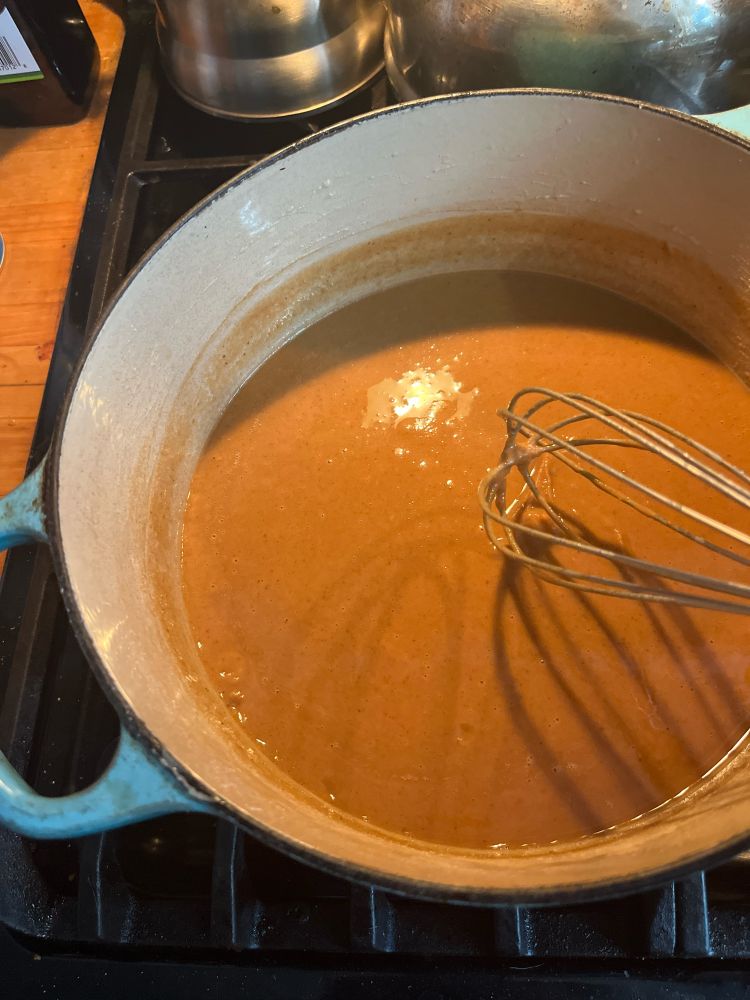 A khaki colored flour, butter, and oil mixture being whisked over heat.