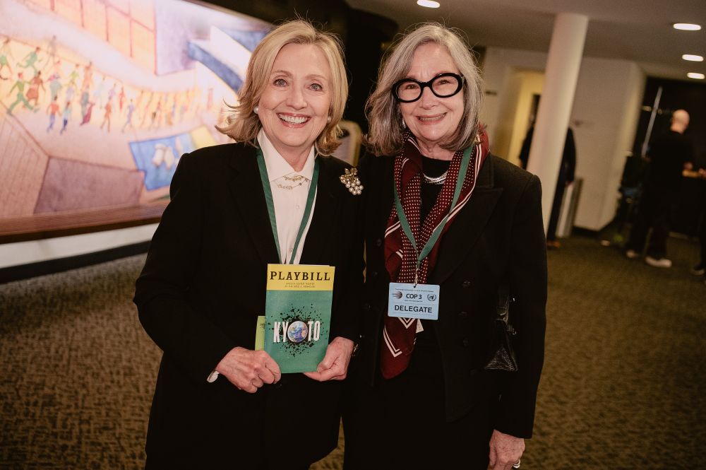 2 women with one holding a Kyoto Playbill and the other wearing a green lanyard