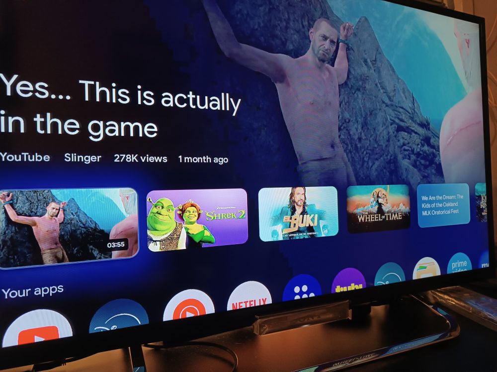 A tv showing a video thumbnail of a shirtless muscular guy in chains with another shirtless man in front of him