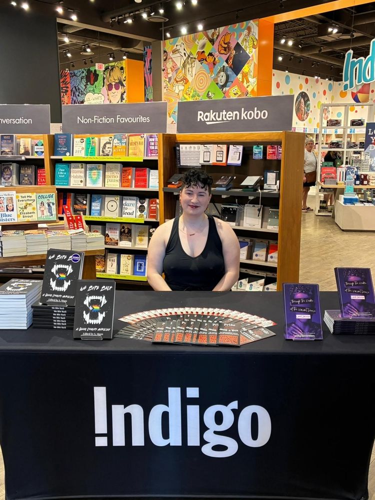 A photo of Pride with a Bite Co-Founder Sarah Laudenbach behind her signing table.