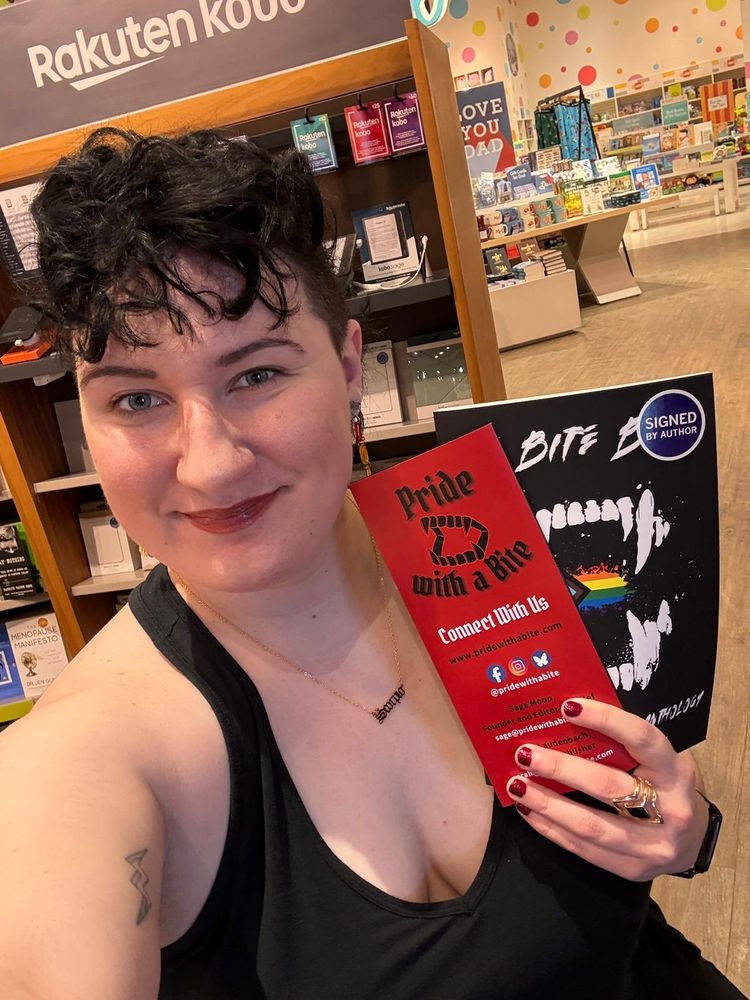 A photo of Pride with a Bite Co-Founder Sarah Laudenbach holding a brochure and signed copy of "We Bite Back."