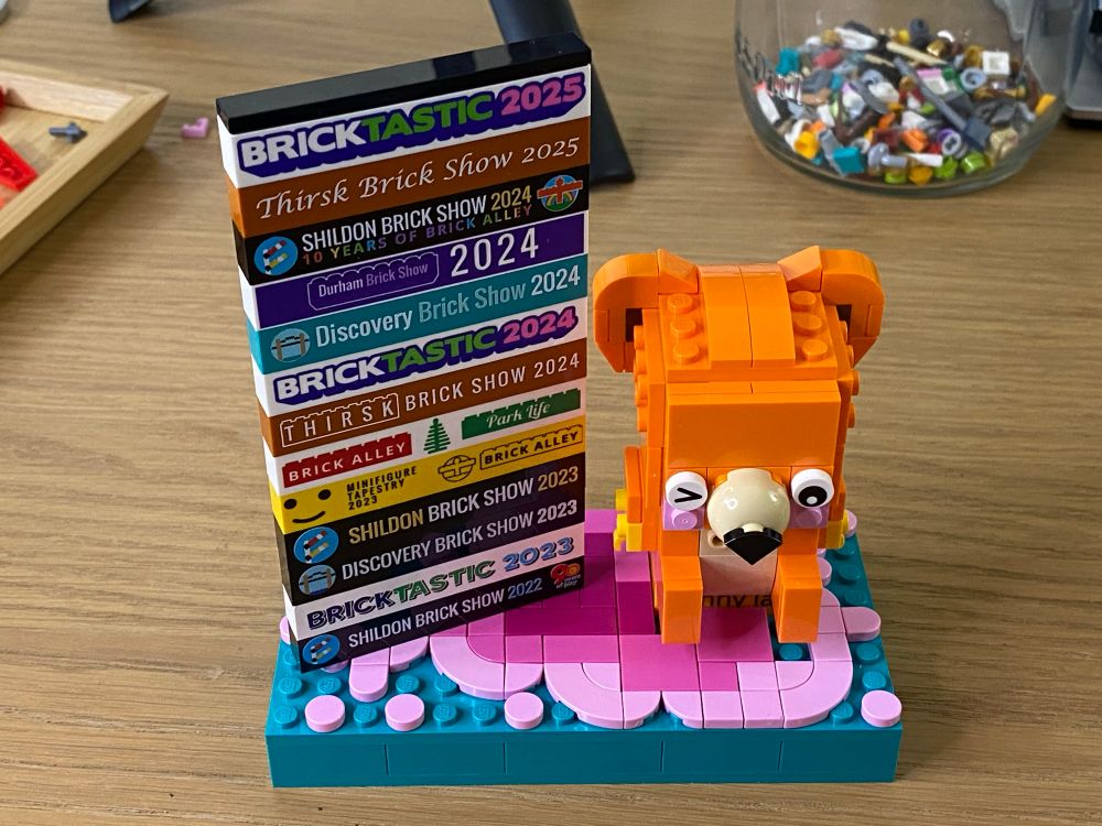 An orange bear made of LEGO next to a stack of show bricks.