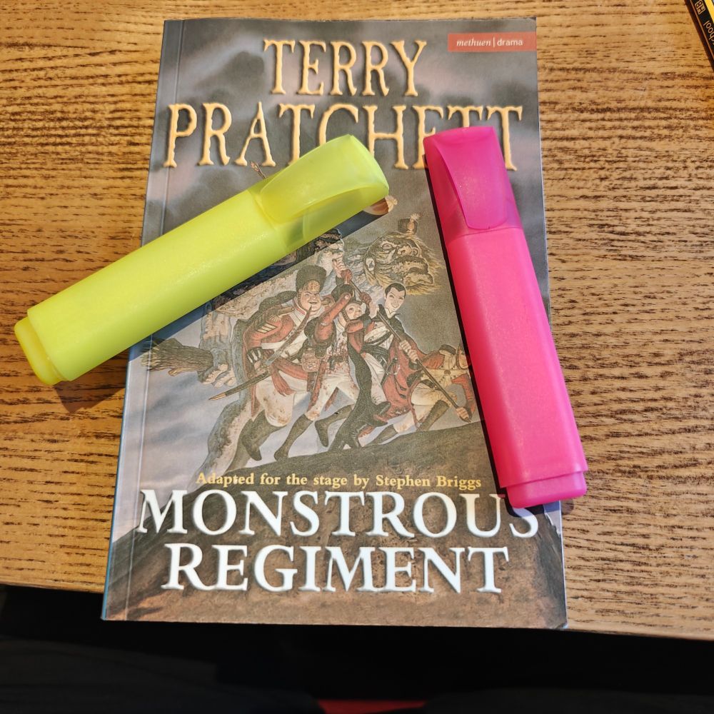 The script for Terry Pratchett's Monstrous Regiment adapted for the stage by Stephen Briggs, with a yellow and pink highlighter pen sat in it.