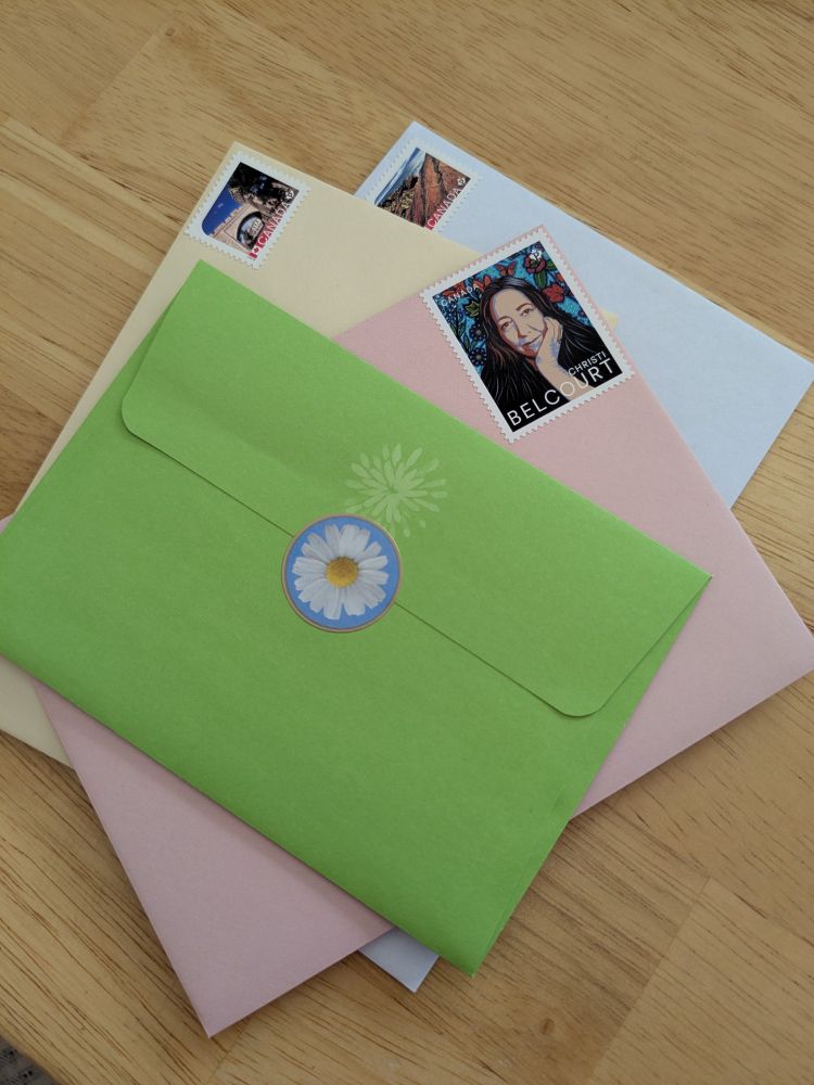 Stack of four greeting cards with different coloured envelopes, stamped and ready to mail. No addresses are showing for privacy concerns.