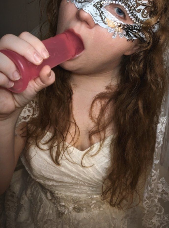 Photo of me with my mouth around a large pink dildo wearing a wedding dress.