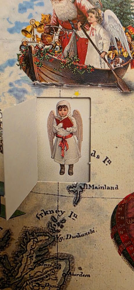 A small child dressed up as an angel, with white wings, holding a red book of music.