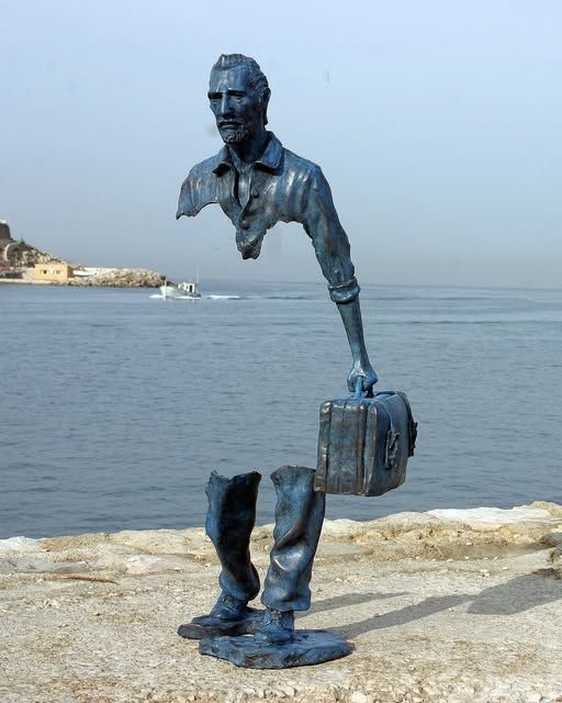 One of the Les Voyageurs by Bruno Catalano.

A metal sculpture of a man holding a battered suitcase. One are and most of his body from the third button of his shirt to below his kneecaps is missing.

Located seaside at Marseille-Fos Port
