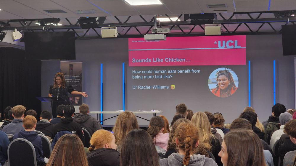 Rachel onstage in front of a title slide at an Education in Action event.
