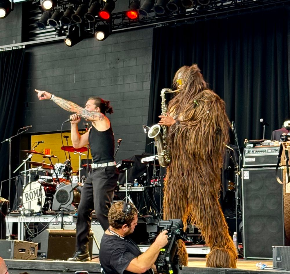 Photo of a Sasquatch wearing sunglasses and playing saxophone along with a human man singing