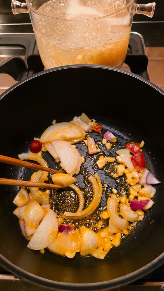 the process of frying vegetables and cooking pasta