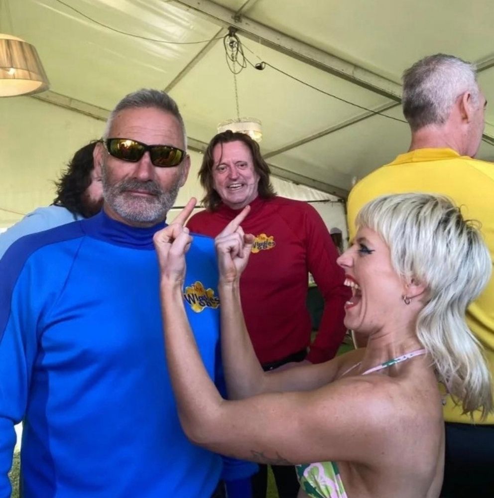 Amy from Amyl and the Sniffers double flipping off Anthony, the blue wiggle from The Wiggles.