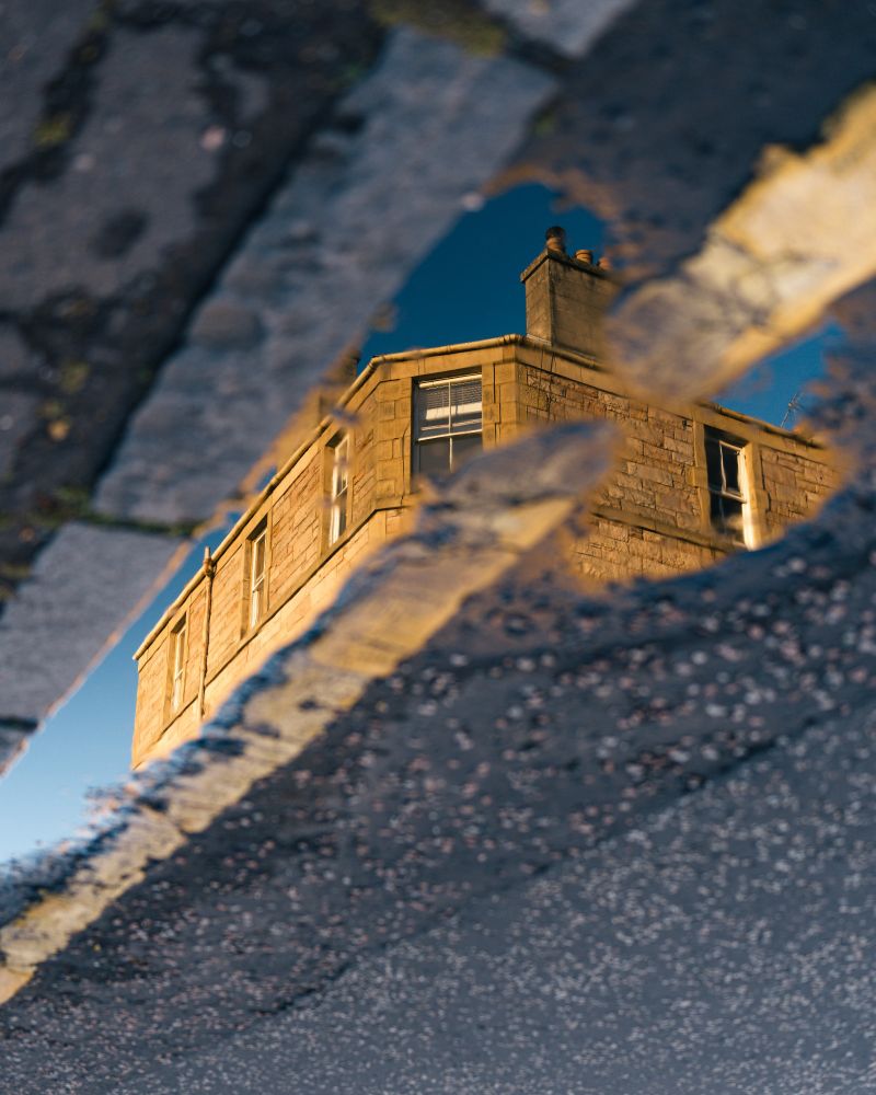 Building seen in a puddle reflection