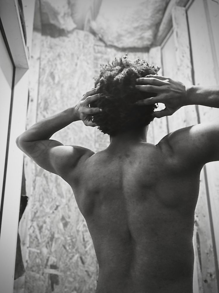 Light Pedding performs a lat spread adjacent pose while using monochrome filtering on a black and white photo of themselves. It’s giving fro. It’s giving shoulders. It’s giving intimacy.