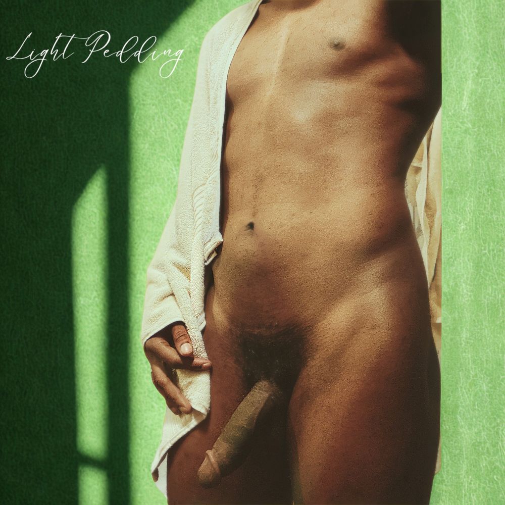 Light Pedding poses in front of an edited green background covered in of soft diffused light with their logo in white on the left most upper corner of the screen. The dark skinned model is nude and serving Gock. 