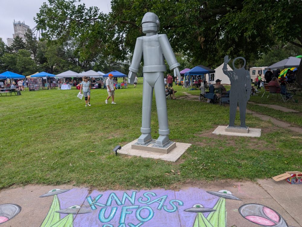 Kansas UFO Day sidewalk chalk mural in front of a statue of the space guy from The Day the Earth Stood Still. In Geneseo, Kansas