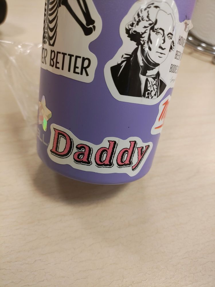 A sticker that says "Daddy" in pink letters 
