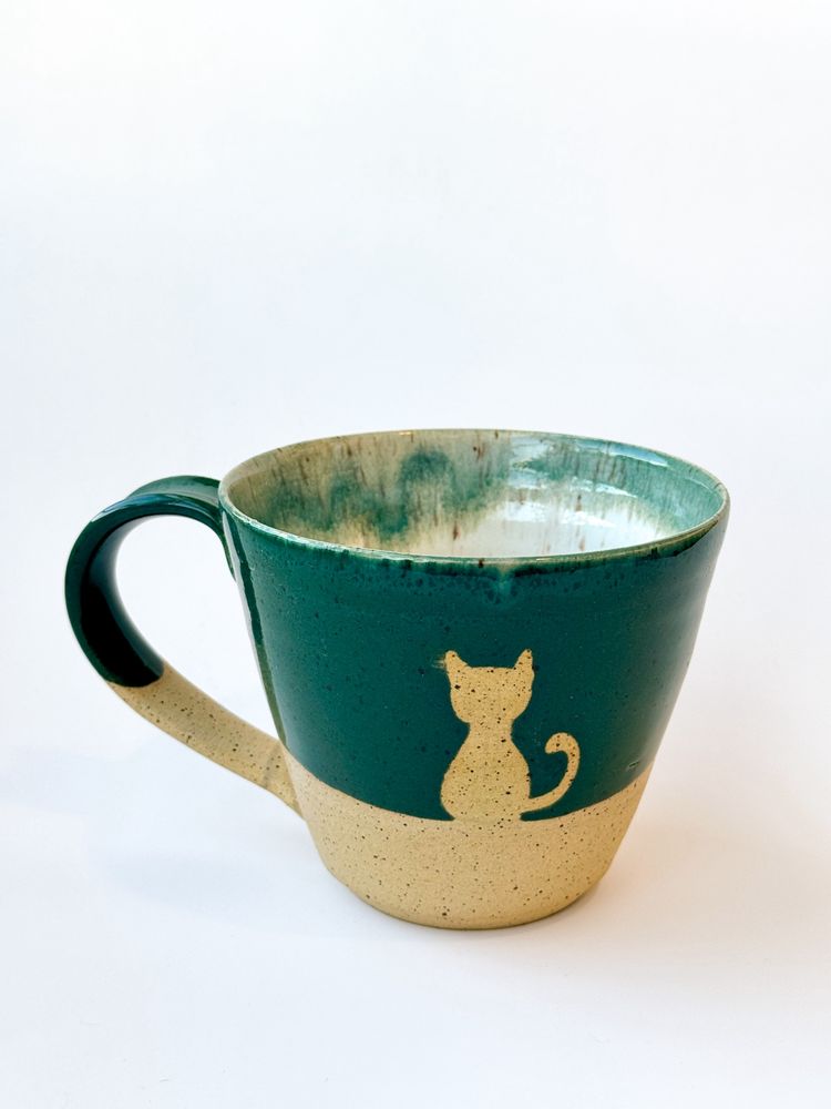 Green and tan mug with a cat design sits on a plain white background 