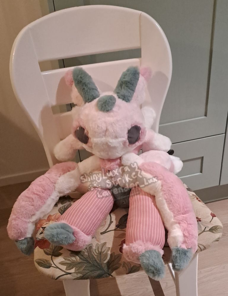 Picture of comfy friends Lurantis, custom handsewn plush by me, sitting on a chair in my kitchen