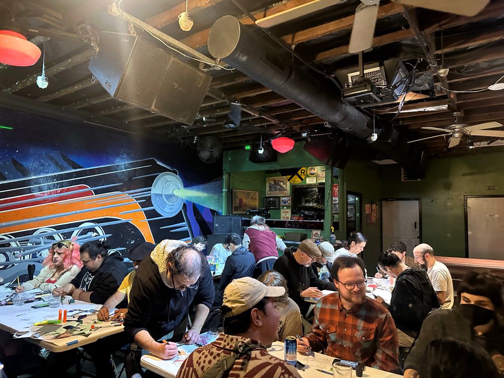 A photo of sketchparty at whistlestop bar San Diego. Paper is put out on tables and everyone makes some art.