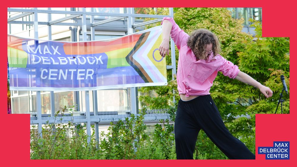 man dancing in front of a pride flag including the logo of the Max Delbrück Center