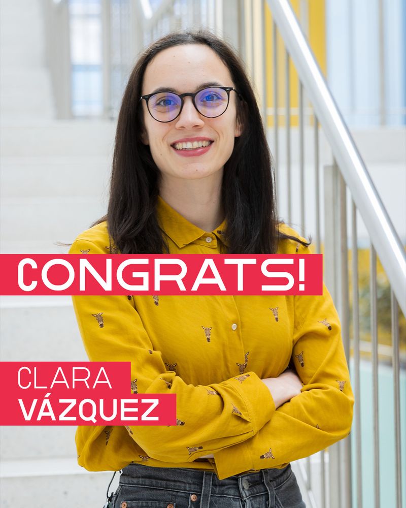 Portrait photo with text overlay: The image shows a woman standing on an indoor staircase, smiling at the camera. She wears glasses and a mustard yellow shirt with a bee pattern. Overlaid white sans-serif text appears in red boxes; across the center, it reads “CONGRATS!” – and at the lower left, it reads “CLARA VÁZQUEZ” in all caps.