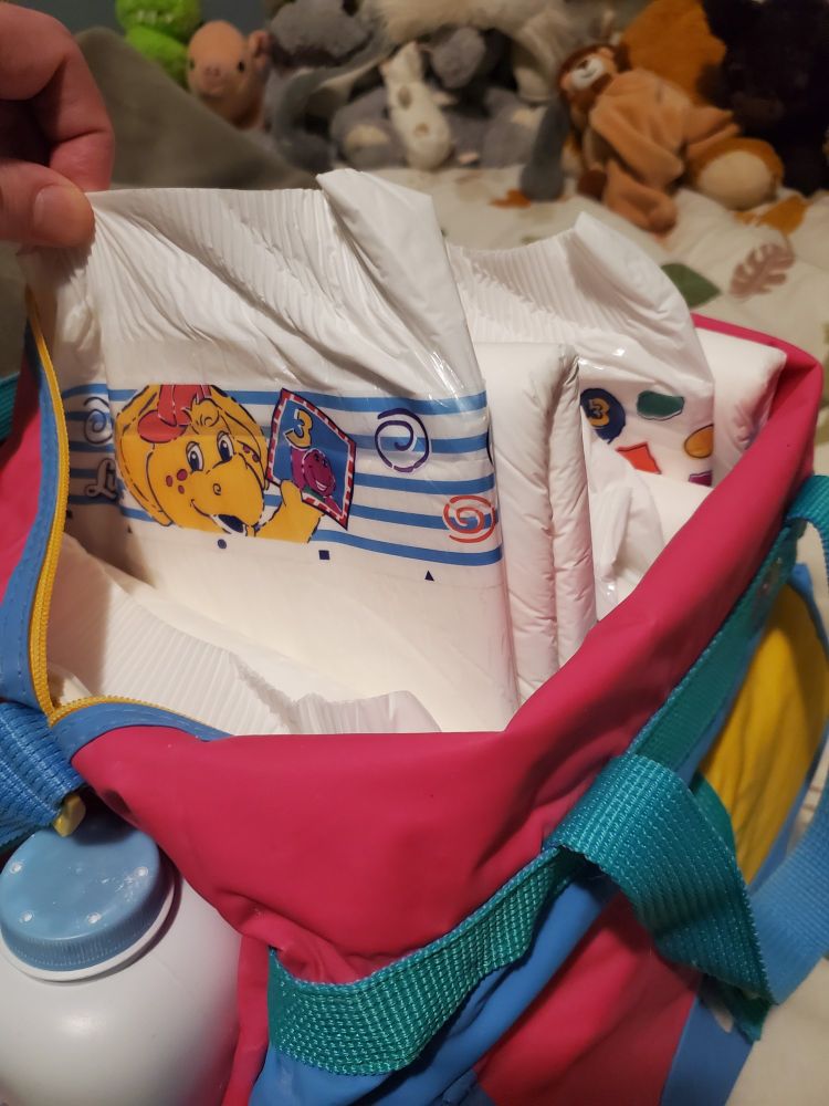 90s color block diaper bag with a Luvs-styled adult diaper featuring BJ from Barney being lifted out from an assortment