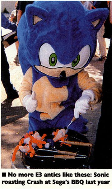 A photo from a magazine of person in a Sonic the Hedgehog costume standing by a barbeque with three Crash Bandicoot plush toys. Sonic is giving a thumbs up and poking at the toys with an implement. 

A caption below the image reads: No more E3 antics like these: Sonic roasting Crash at Sega's BBQ last year.