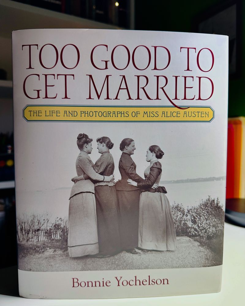 The book cover features two couples of women embracing, standing in front of a body of water.