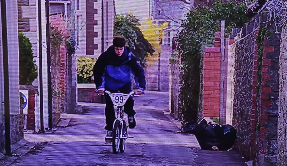 Screenshot of Danny dyer cycling down a Cardiff backstreet in the movie human traffic 