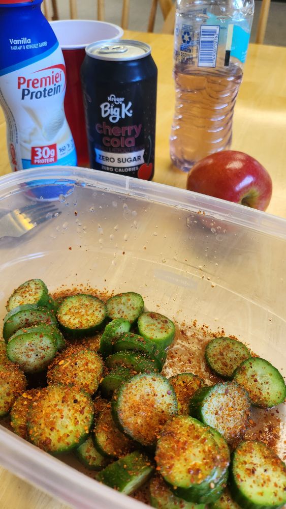 A vanilla protein shake, a zero sugar cherry cola, an electrolyte drink, an apple, persian cucumbers with chili powder