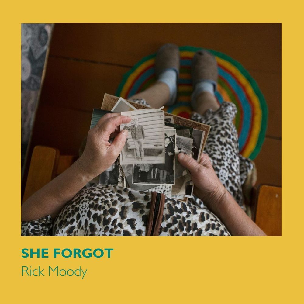 A photo of a stack of old photos in an old woman's lap. She has white wrinkled skin and her feet are slipped and resting on a bright green, yellow, red, and blue rug. Text on a yellow background reads "She Forgot" and "Rick Moody." 