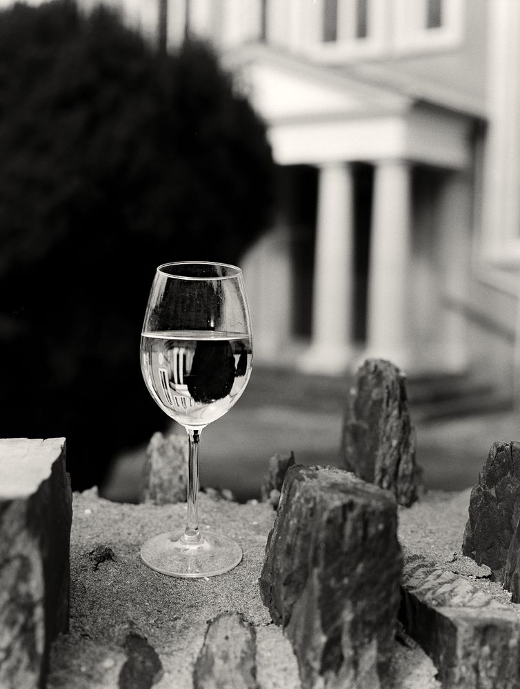 Black and White image of a glass of white wine left on the wall of a chapel near the town centre of Newcastle Emlyn. 

The image made on a Bronica ETRS using Ilford FP4+ film stock. The camera shoots 645 format negatives (The Texas Half Frame format)