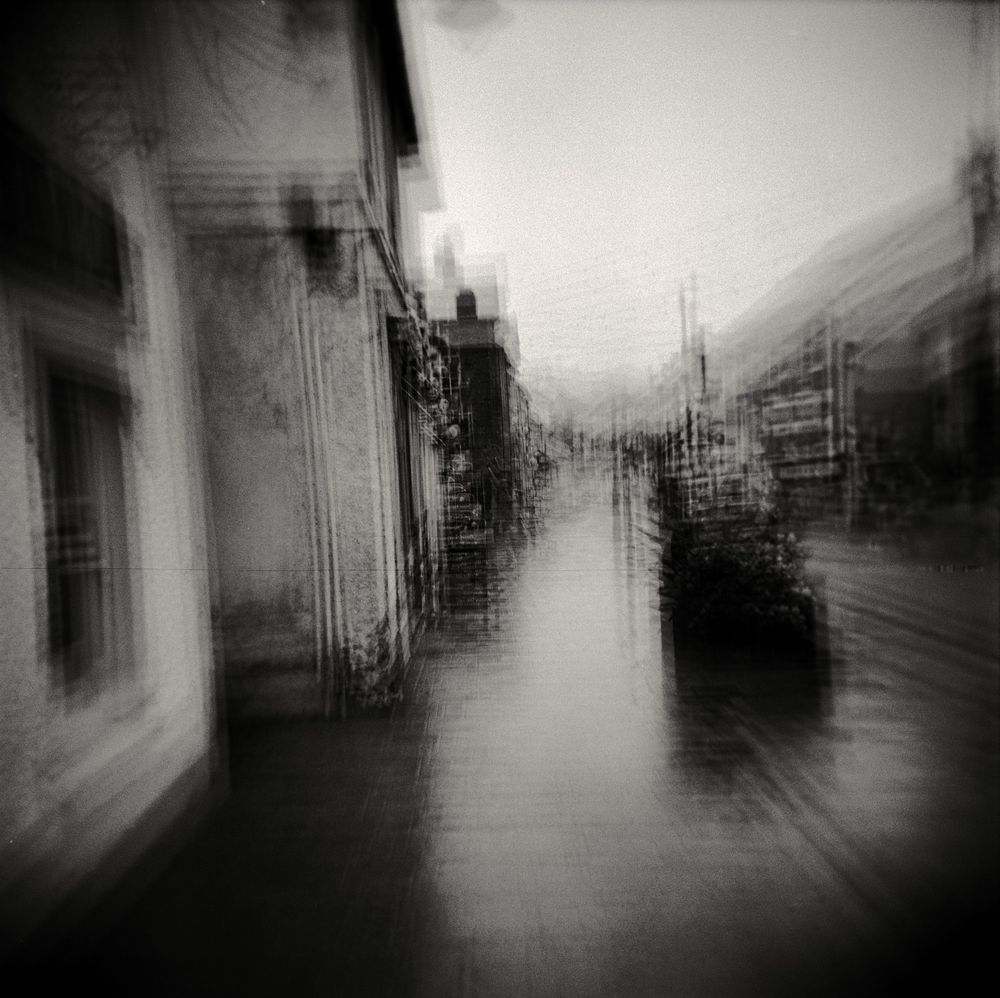 A black and white multiple exposure image of Newcastle Emlyn on a very wet day. The camera, a Holga GSN120 needed 8 exposures to bring the negative up to the required exposure. All exposures are mis-aligned a little to create a blurred surreal rendition of the scene. 