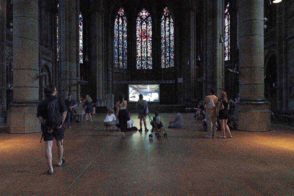a group of people in a large room with stained glass windows