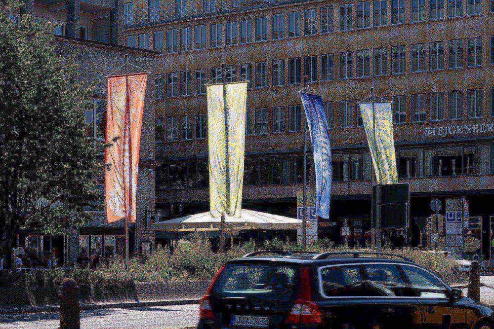 eine Gruppe von Fahnen auf Stangen vor einem Gebäude