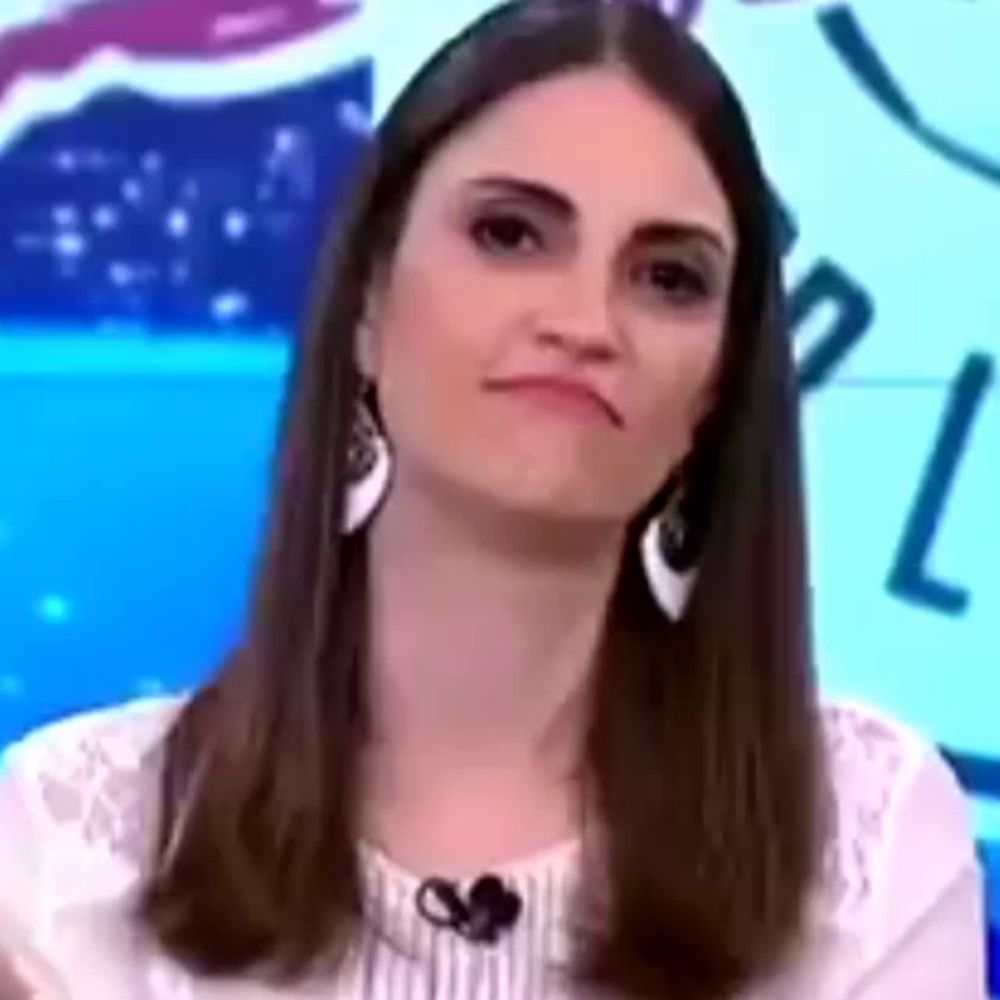 a woman is making a funny face while sitting in front of a pepsi sign .