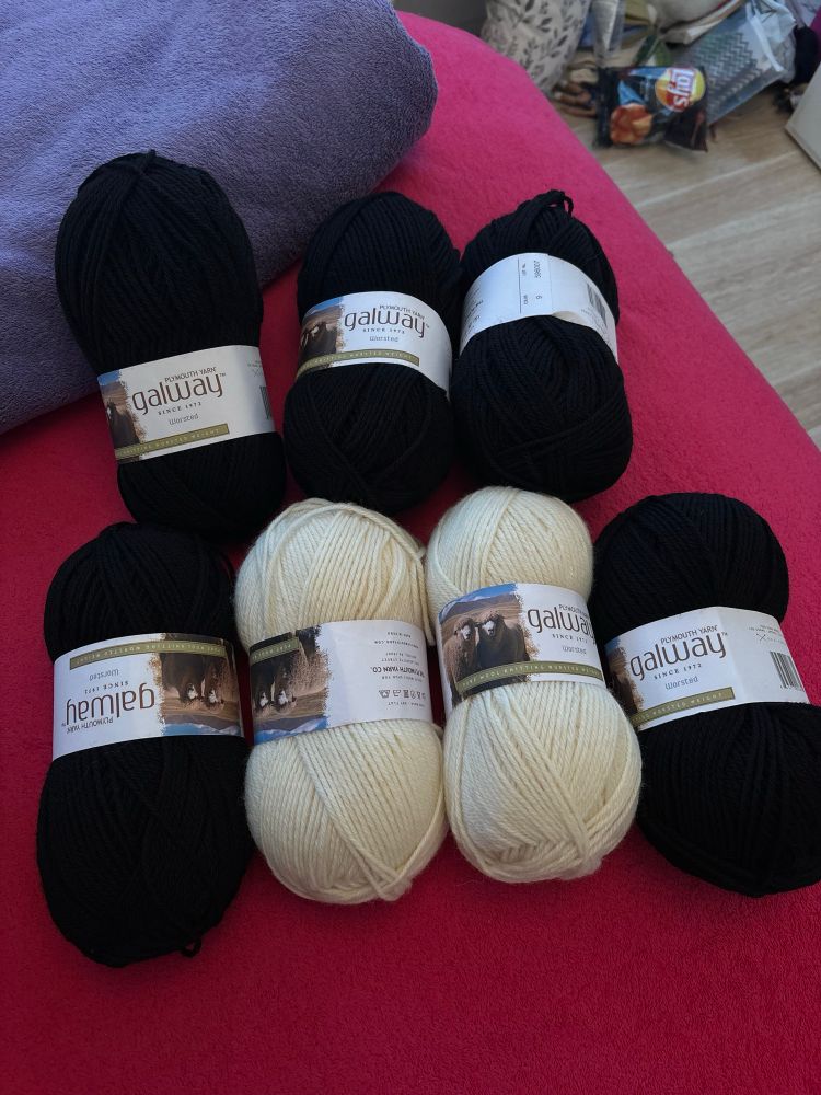 five skeins of plymouth yarn galway worsted in black, and two skeins in cream