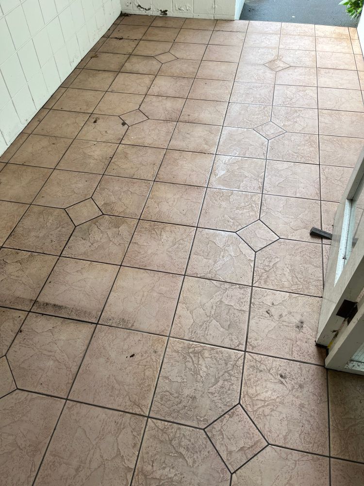 Photo of a tiling patio floor. It consists of 3x3 square tiles with diamonds in the corner of each 3x3 section. Has dirty/mouldy patches.