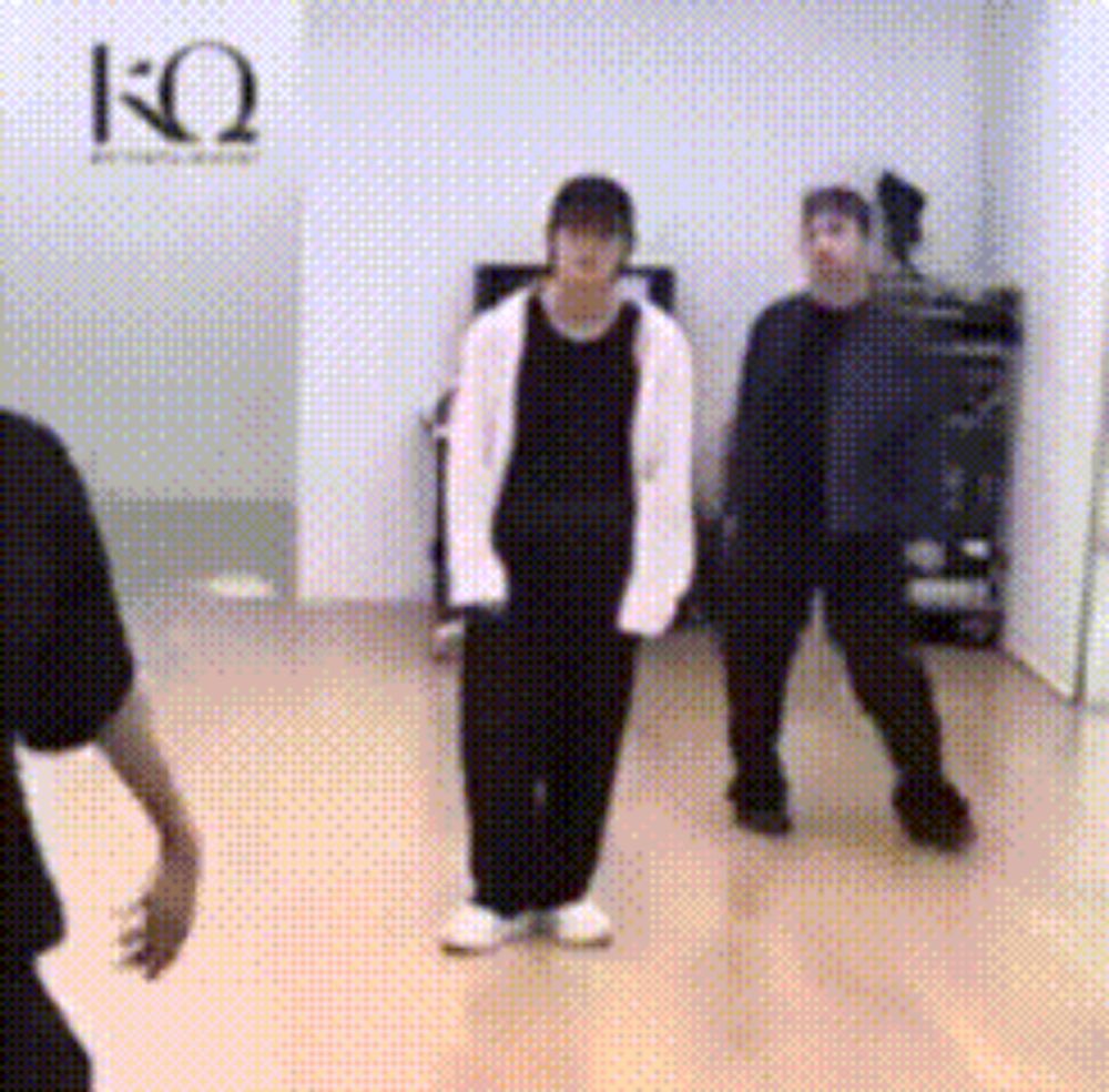 a group of people are dancing in a room with a sign that says kq on it .